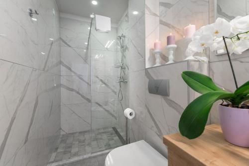 a bathroom with a shower with a toilet and a plant at Hotel Maritimo in Makarska