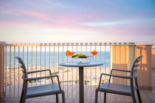 a table with two chairs and a plate of food on a balcony at Hotel Bellevue in Rimini