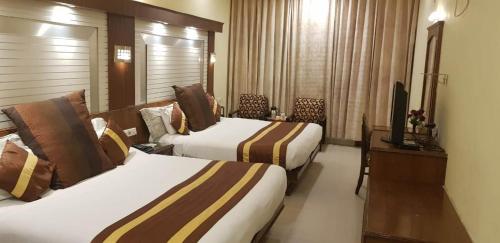 a hotel room with two beds and a television at Hotel CJ International in Amritsar