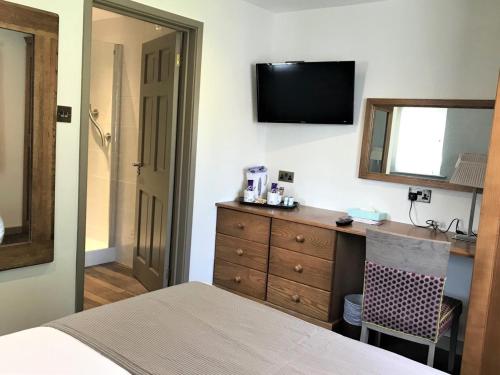 a bedroom with a bed and a dresser and a mirror at La Barbarie Hotel in St Martin Guernsey