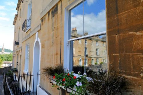 a window on a building with flowers in a window box at Southcot Place, Apartment With Garden in Bath