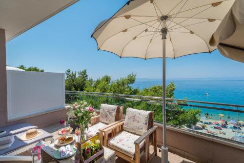 a patio area with a table, chairs, and umbrella at Hotel Maritimo in Makarska