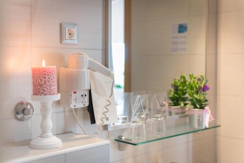 a bathroom with a candle and glasses on a glass shelf at Hotel Maritimo in Makarska