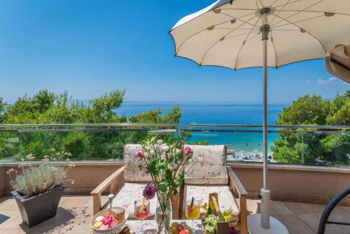 a patio with a table and an umbrella and the ocean at Hotel Maritimo in Makarska