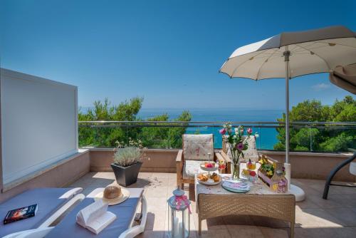 a patio with a table and an umbrella and the ocean at Hotel Maritimo in Makarska