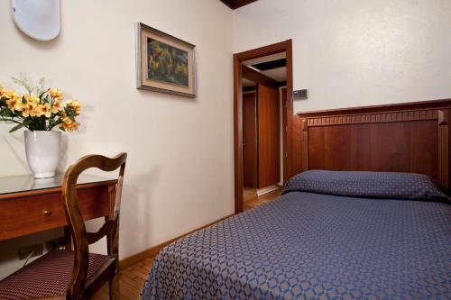 a bedroom with a bed and a desk with a vase of flowers at Hotel Bellevue in Rimini