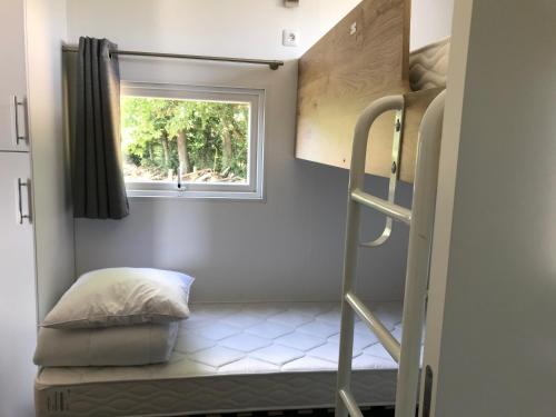 a small room with a bunk bed and a window at L Orée Du Bois in Moncheux