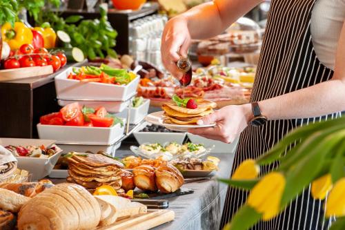 een vrouw serveert eten in een buffet bij Spatz Aparthotel in Krakau