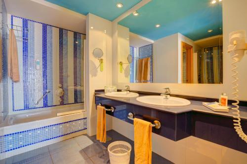 a bathroom with two sinks and a shower and a tub at SBH Crystal Beach Hotel & Suites - Adults Only in Costa Calma