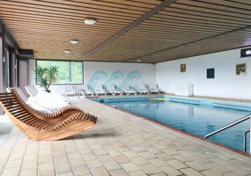 a large swimming pool with chairs and a swimming pool at Ferien vom Ich, Bayerischer Wald, Hotel & Restaurant in Neukirchen