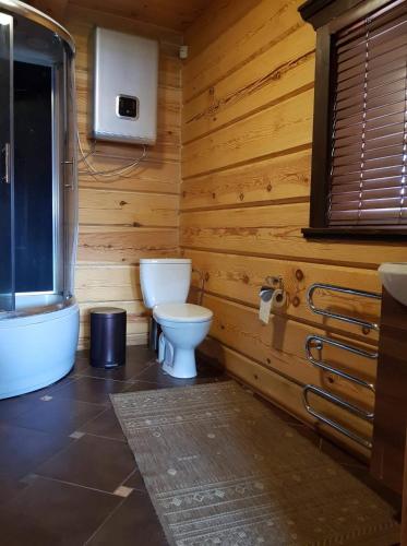 a wooden bathroom with a toilet and a tub at Namukas su ežero pakrante Trakai ,Viesų vila in Salkininkai