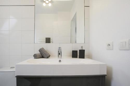 a white bathroom with a sink and a mirror at Dreamyflat - Champs Elysées in Paris