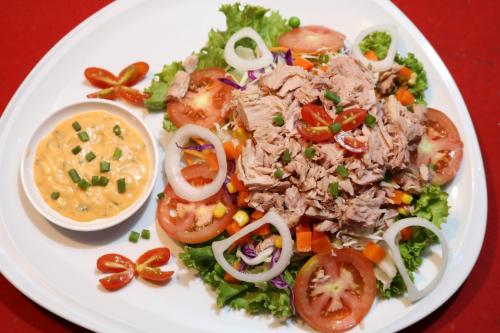 a white plate of food with tuna salad and tomatoes at Hideaway Guest House And Bar in Pattaya Central