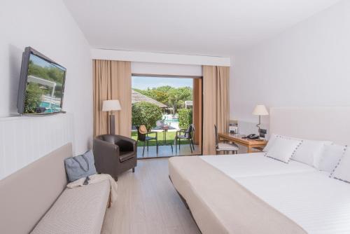 a hotel room with a bed and a chair and a balcony at La Costa Hotel Golf & Beach Resort in Pals