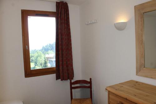 een kamer met een raam met een stoel en een bureau bij Résidence Grand Bois A1118 Clés Blanches in La Tania