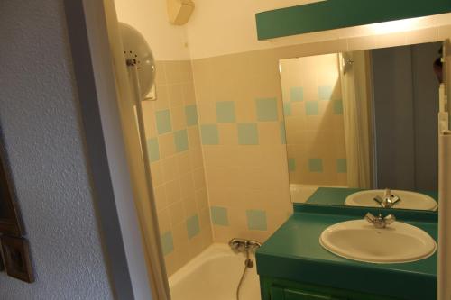 een badkamer met een wastafel, een bad en een spiegel bij Résidence Grand Bois A1118 Clés Blanches in La Tania