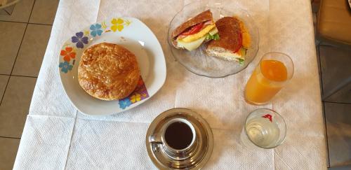 a table with a plate of sandwiches and a glass of orange juice at Alexia's Apartments in Rio