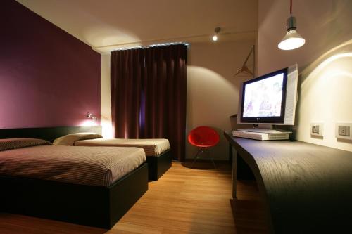 a hotel room with two beds and a flat screen tv at Hotel San Francesco in Borgomanero