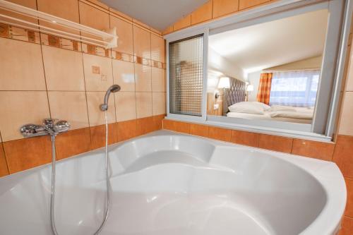 a bath tub in a bathroom with a window at Hotel Čingov Slovenský raj in Smižany