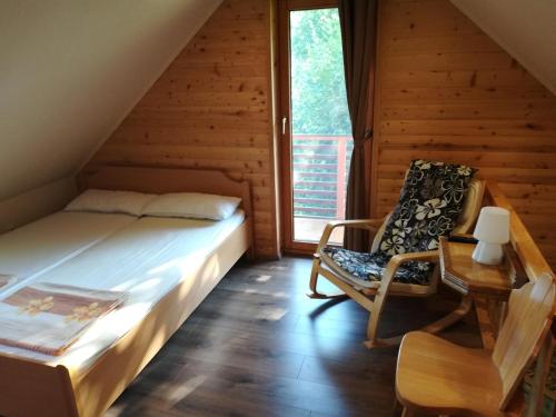 a bedroom with a bed and a chair and a window at Brunarica Lorentia in Bizeljsko