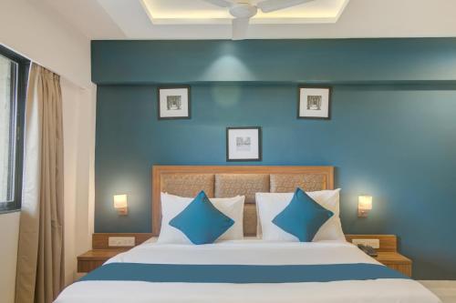a bedroom with a large bed with blue walls at Hotel Palm Beach Pride in Mumbai