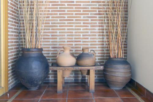 three vases sitting on a table next to a brick wall at Hotel Arco San Vicente in Ávila