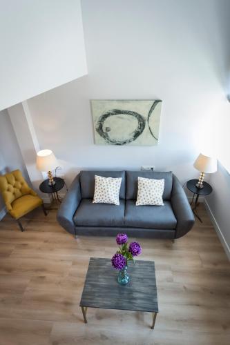 a living room with a couch and a table with purple flowers at Casa de la Merced Suites in Málaga