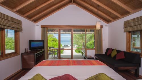 a bedroom with a bed and a tv and a couch at Kuredu Island Resort & Spa in Kuredu
