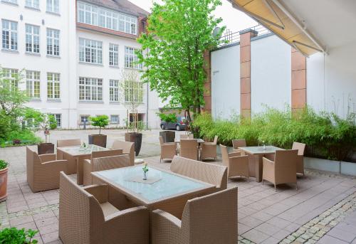 patio ze stołami i krzesłami oraz budynek w obiekcie Residenz Hotel Detmold w mieście Detmold