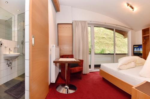 ein Schlafzimmer mit einem Bett und einem Waschbecken sowie ein Badezimmer in der Unterkunft Ferienwohnen Mattle in Kappl