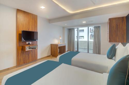 a hotel room with a bed and a tv at Hotel Palm Beach Pride in Mumbai