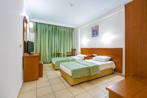 a hotel room with two beds and a television at Alanya Beach Hotel in Alanya