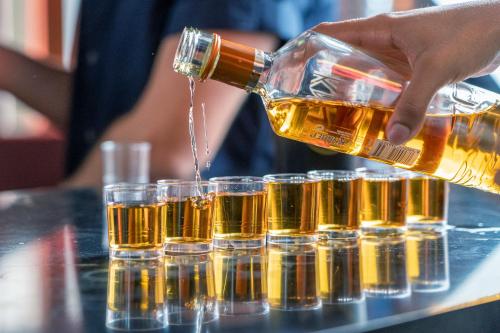 a person pouring a bottle of beer into a group of glasses at Cats Hostel Madrid Sol in Madrid