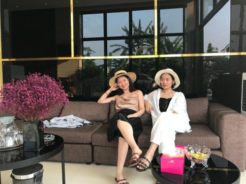 two women sitting on a couch in a living room at Windy Hotel Quang Binh in Dong Hoi