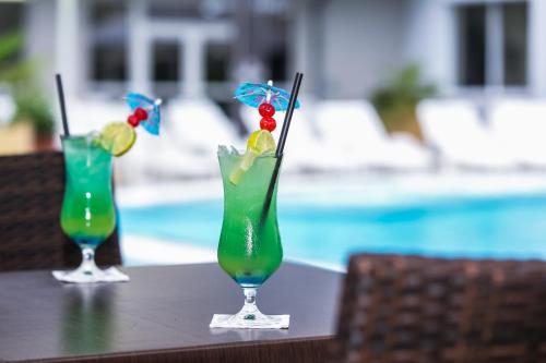 two cocktails sitting on a table next to a pool at Ambient Hotel & Thermal Spa in Sikonda