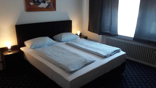 a bed with two pillows on it in a room at Hotel Elsenztal in Bammental
