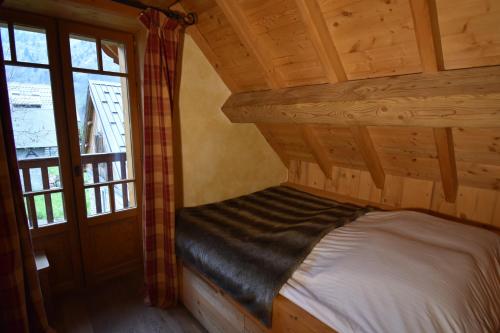 a bedroom with a bed in a log cabin at VAUJANYLOCATIONS - Chalets Clovis I & II in Vaujany