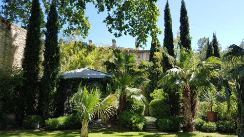 a garden with palm trees and a building at La Divine Comédie-Suites Deluxe in Avignon