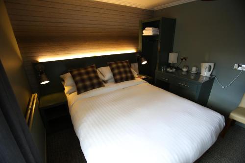 a bedroom with a large white bed with a wooden headboard at Kings Arms Hotel in Melrose