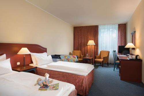 ein Hotelzimmer mit zwei Betten mit Puppen drauf in der Unterkunft SORAT Hotel Brandenburg in Brandenburg an der Havel