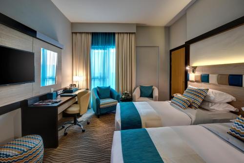 a hotel room with two beds and a desk at City Avenue Hotel in Dubai