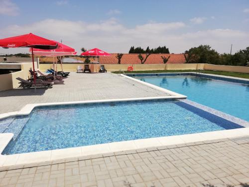 una gran piscina con sombrillas y sillas rojas en Nefama Pensao en Ourique