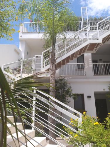 a white building with a palm tree in front of it at Hotel Belvir in Villasimius