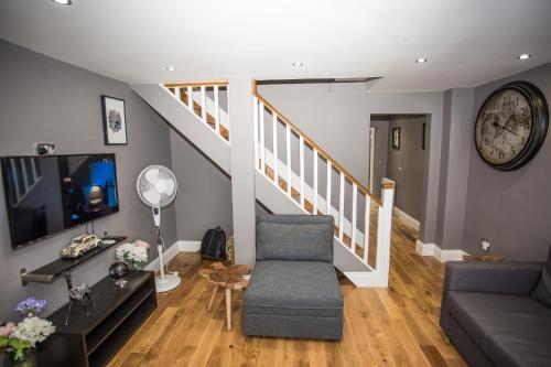 a living room with a couch and a staircase at Sunset Homes in London