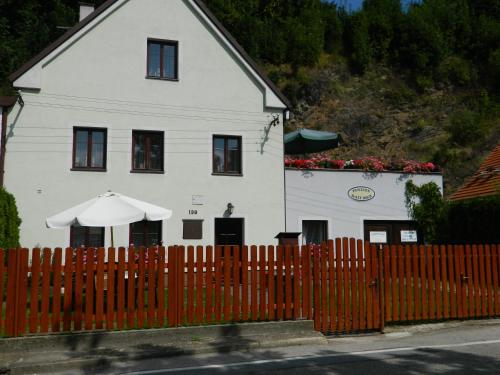 a white house with an umbrella and a fence at Penzion Sv. Duch in Český Krumlov