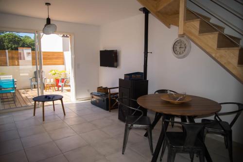 uma sala de estar com uma mesa e cadeiras e uma televisão em Les Terrasses de Bella Vista - Belle maison bord de mer em Saint-Vincent-sur-Jard