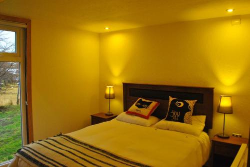 a yellow bedroom with a bed with pillows on it at Martín Pescador Cabañas in Coihaique