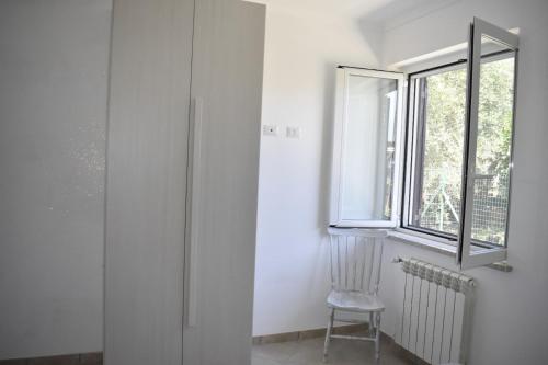 Cette chambre blanche dispose d'une chaise et d'une fenêtre. dans l'établissement Da Nonna Laura al Circeo, à San Felice Circeo