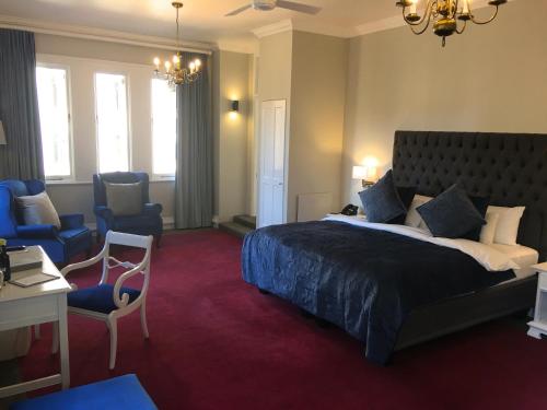 um quarto com uma cama grande, uma secretária e cadeiras em Rand Club Suites em Joanesburgo