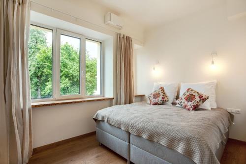 a bedroom with a bed with two pillows and two windows at Bright and Cosy 1BDR apartment Kaunas Centre in Kaunas